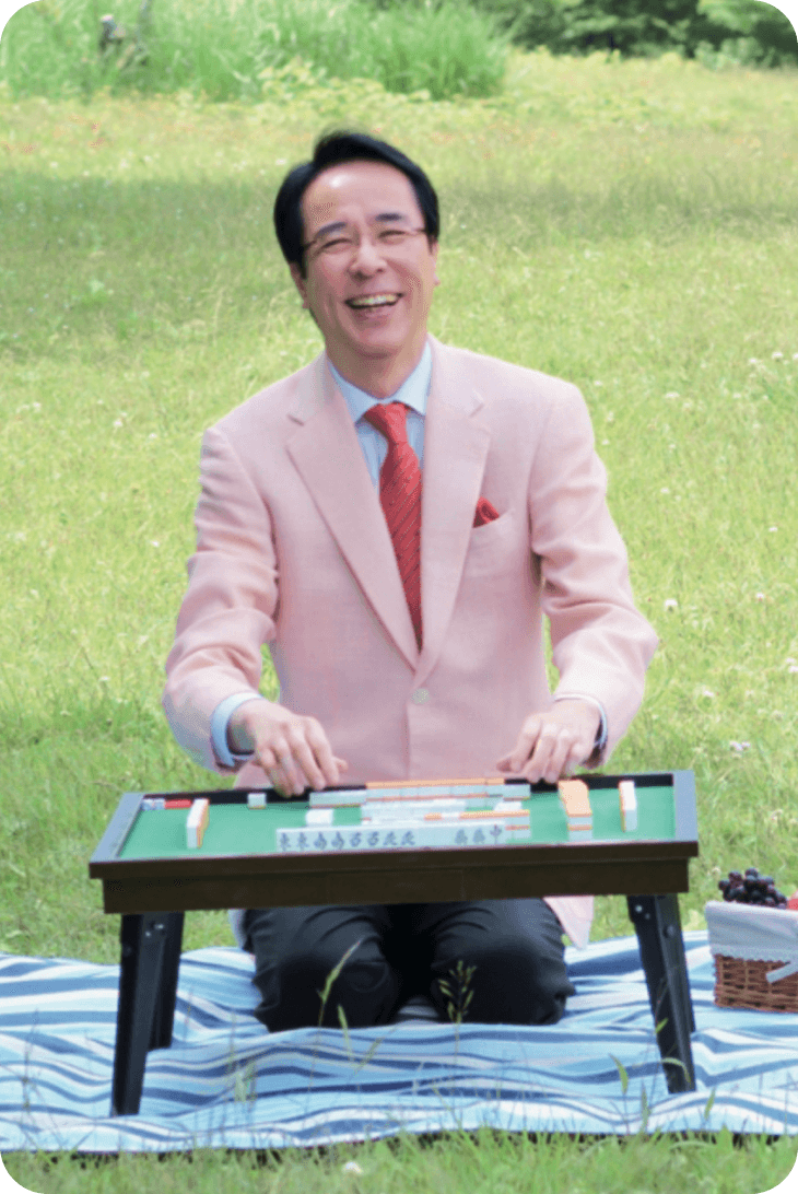 芝生の上で麻雀卓を前に笑顔を見せる土田浩翔プロ